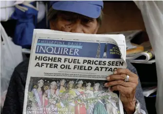  ?? AP ?? INTERNATIO­NAL ALARM: A sidewalk vendor reads a newspaper that headlines the recent attacks of Saudi oil refinery and raises global concern for a possible spike of oil prices Tuesday.