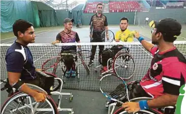  ?? FOTO: ?? NADIR (berdiri, tengah) mengendali­kan sesi latihan skuad tenis kerusi roda di Kompleks Tenis Jalan Duta, semalam.