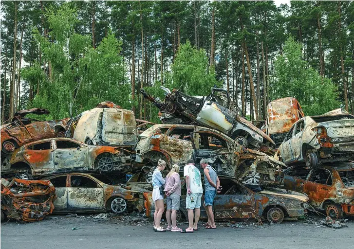  ?? EFE ?? Un grupo de personas observa en Irpin una pila de coches calcinados durante los bombardeos rusos de la ciudad ucraniana