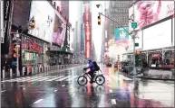  ?? Getty Images ?? A bike messenger rides through the rain at Time Square in New York City on Friday. The U.S. budget deficit surged 218 percent to a record $3.1 trillion in the fiscal year ended Sept. 30 due to a massive increase in spending to help the economy weather the pandemic.