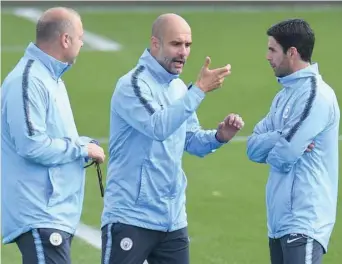  ?? — AFP ?? Manchester City’s manager Pep Guardiola (centre) talks with Mikel Arteta (R) during a training session.