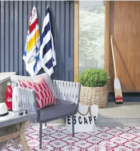  ??  ?? The red and white outdoor carpet has a country design, while the side table with a concrete top is a more modern cottage touch.