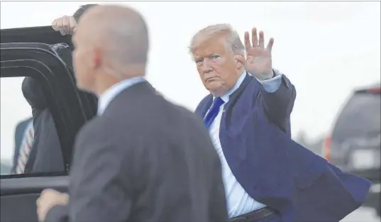  ?? Susan Walsh The Associated Press ?? President Donald Trump waves before getting into his vehicle after arriving at Palm Beach Internatio­nal Airport in West Palm Beach, Fla., on Friday. The president and his family are spending the weekend at their Mar-a-Lago estate.