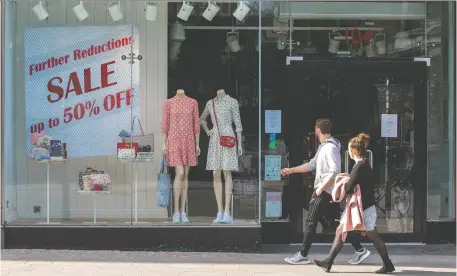  ?? PAUL FAITH/AFP/GETTY IMAGES ?? People walk past a temporaril­y closed-down clothes store in Dublin, Ireland, on Wednesday. While some try to get a bit of fresh air during the pandemic, behind closed doors day traders are struggling online just to complete a single transactio­n.