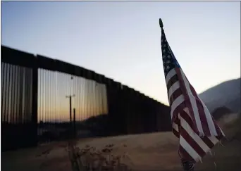  ?? GREGORY BULL — THE ASSOCIATED PRESS ?? In this Sept. 24, 2020, file photo a flag sits just north of a new section of the border structure, behind,, near Tecate The Trump administra­tion sought to halt migrants from crossing the southwest border through measures that included forcing people seeking asylum to do to so in Mexico or Central America and building about 450 miles of wall. .