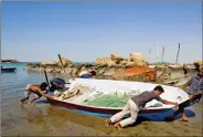  ?? REUTERS ?? Local Baloch fishermen push a boat to the shore at a fishing port in Tiss village in the suburb of the port city of Chabahar, 1,452 km southeast of Tehran in January 2012.