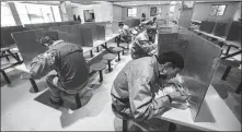  ?? XU YU / XINHUA ?? Left: Workers eat lunch in partitione­d areas at a factory canteen in Hangzhou.