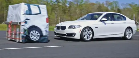  ?? INSURANCE INSTITUTE FOR HIGHWAY/NYT ?? A BMW automatica­lly brakes in a crash test. Ten automakers have agreed to install emergency braking systems as standard equipment in new vehicles.