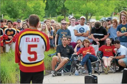  ?? PETE BANNAN — DIGITAL FIRST MEDIA ?? Above, Drew Smethurst, a friend of former West Chester East hockey star Michael Eland, wears Eland’s Viking hockey jersey as he speaks during a “Celebratio­n of Life” at East Friday evening, with Eland’s family and friends looking on. Michael Eland died in the early morning hours of July 16 after a one-car crash in Delaware. Below, Stephen Eland, Michael’s father, hugs a classmate of his son’s during the event.