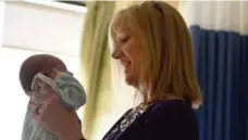  ??  ?? Sarah Simpson, a social worker, comforts a baby in St. Joseph’s NICU.