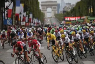  ?? CHRISTOPHE ENA, THE ASSOCIATED PRESS ?? The pack with Britain’s Chris Froome, wearing the overall leader’s yellow jersey, rides on the Champs Élysées with the Arc de Triomphe in the background on the final day of the Tour de France on Sunday.