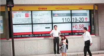  ?? — AFP ?? Pedestrian­s walk past a stock quotation board flashing the current foreign exchange rate of the yen against the US dollar in Tokyo on August 15, 2017.