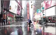  ?? Getty Images ?? A bike messenger rides through the rain at Time Square in New York City on Friday. The U.S. budget deficit surged 218 percent to a record $3.1 trillion in the fiscal year ended Sept. 30 due to a massive increase in spending to help the economy weather the pandemic.