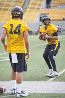  ?? Amy Osborne / Special to The Chronicle ?? Sophomore Ross Bowers (right), one of five quarterbac­ks in the mix to start, runs drills at Cal’s first spring practice.