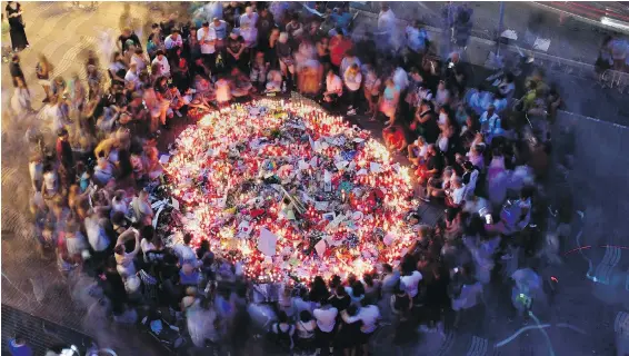  ?? MANU FERNANDEZ, THE ASSOCIATED PRESS ?? People gather Friday at a memorial tribute to the victims on Barcelona’s historic Las Ramblas promenade at the Mosaic del Pla de l’Os designed by Spanish painter Joan Miró i Ferrà. The mosaic is embedded in the pavement where a van stopped after...