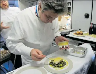  ?? PHOTOS: LESLEY CHESTERMAN ?? Chef Michel Roth assembles a dish of pollack with mussel sauce, salt-cured lemon zest and simmered vegetables on board an Air France airplane.