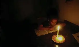  ??  ?? A girl reads at her house with the help of a candle during blackouts on Tuesday in Caracas. Photograph: Getty Images
