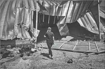  ?? LIBKOS/AP PHOTO ?? A woman walks among debris Friday at a farm storage building destroyed during a Russian attack in Odesa region, Ukraine. A missile barrage injured two people, damaged equipment and destroyed 100 metric tons of peas and 20 metric tons of barley, regional Gov. Oleh Kiper said.