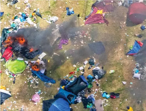  ?? ?? Aftermath: Tents, some simply abandoned, some still burning, amid the debris left behind at Reading campsite