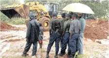  ??  ?? POLICE keep a close watch as a grader clears the road in Chimaniman­i, Zimbwabwe. According to the government, cyclone Idai has killed more than 80 people, although residents say the figure could be higher.