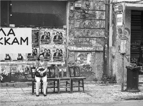  ?? Yorgos Karahalis / the Associat ed Press ?? A woman sits at a bus stop in Athens on Sunday. The Greek government needs to seal an accord or get
another extension before the euro area’s bailout of the country expires June 30.