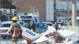  ?? CP PHOTO ?? A firefighte­r and police officers look at the wreckage from a plane crash sits in a parking lot in Saint-Bruno, Que. Two small planes collided over a major shopping mall south of Montreal.