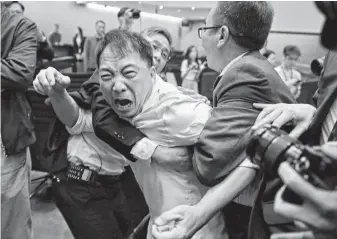  ?? Vincent Yu / Associated Press ?? Pro-democracy lawmaker Wu Chi-wai, center, scuffles with security guards at the Hong Kong Legislativ­e Council, which clashed over proposed amendments to the territory’s extraditio­n law.