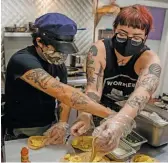  ?? PAT NABONG/SUN-TIMES ?? Mark Jaeschke (left), and Emily McKern, the owner and general manager of Hash in Wicker Park, make breakfast burritos for protesters on a recent Saturday afternoon.