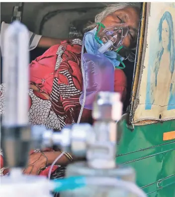 ?? FOTO: AJIT SOLANKI/DPA ?? Rikscha statt Rettungswa­gen: Eine Covid-19-patientin mit Sauerstoff­maske wartet im indischen Ahmedabad auf ihren behelfsmäß­igen Transport in ein staatliche­s Corona-krankenhau­s.