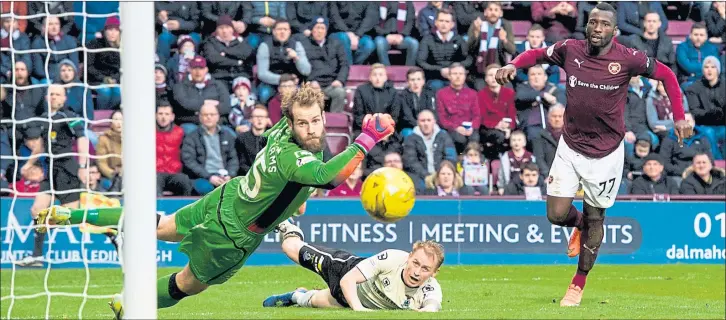  ?? Pictures: SNS ?? HITTING THE SKIDS: An Ismael Goncalves (right) effort skews wide at a muddy Tynecastle on Saturday which Alexandros Tziolis (below) found difficult to play on with Hearts’ passing style.