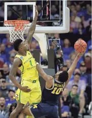  ?? GETTY IMAGES ?? Michigan’s Derrick Walton Jr. (left) puts up a shot as Oregon’s Jordan Bell defends Thursday night.