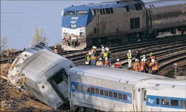  ?? MARK LENNIHAN / AP 2013 ?? An Amtrak train passes a derailed Metro North commuter train in New York City, Dec. 1, 2013. The Trump administra­tion has sought to eliminate safety programs targeting issues such as driver fatigue.