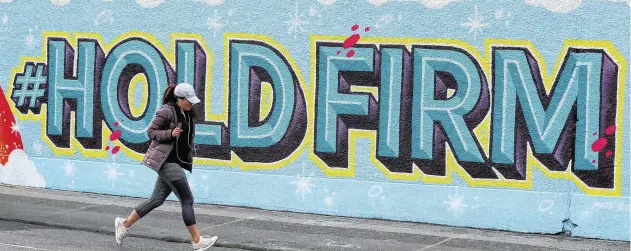  ?? PHOTO: BRIAN LAWLESS / PA WIRE ?? Resolve: A woman runs past a mural in Dublin city centre at the height of the Covid lockdown