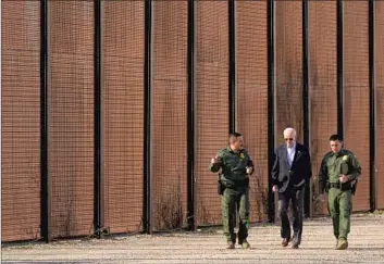  ?? Andrew Harnik Associated Press ?? PRESIDENT BIDEN walks with Border Patrol agents along a fence separating El Paso and Mexico. Biden’s efforts to address a migration surge have angered Republican­s, some Democrats and human rights advocates.