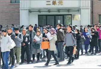  ?? WANG ZHUANGFEI / CHINA DAILY ?? People wait in line to apply for public rental homes in Beijing’s Chaoyang district on Tuesday.