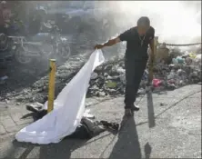  ?? Odelyn Joseph/Associated Press ?? A person lifts a sheet to look at a body lying on the ground Monday after an overnight shooting in the Petion Ville neighborho­od of Port-au-Prince, Haiti.