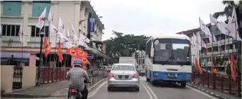  ?? — Photo by Peter Boon ?? GPS and PSB flags line up the pavements on both sides of a road at Sungai Merah in Sibu.