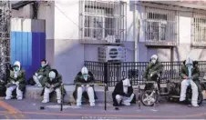  ?? PHOTO: REUTERS ?? Pandemic control workers in protective suits sit in an area that used to be under lockdown, as Covid outbreaks continue, in Beijing on Saturday