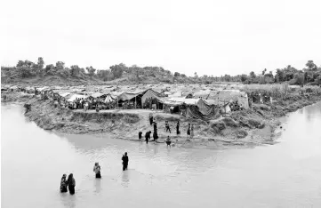  ??  ?? Rohingya refugees cross a stream to reach their temporary shelters at No Man?s Land between Bangladesh-Myanmar border, at Cox’s Bazar, Bangladesh. — Reuters photo