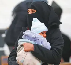  ?? AFP ?? A Syrian mother holds her baby as aid is being delivered to the Al Hol refugee camp in Al Hasakeh in northeaste­rn Syria.