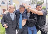  ?? FERNANDO LLANO/ASSOCIATED PRESS ?? Opposition lawmaker Americo De Grazia is led away by bodyguards and a National Assembly employee after he was injured in a melee in congress chambers.