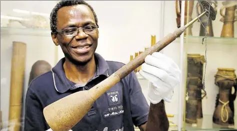  ?? DPA-BILD: C. JASPERSEN ?? Aufwendige Arbeit: der Wissenscha­ftler Ndzodo Awono im Übersee-Museum mit einer Schalmei aus Kamerun