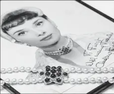  ?? ?? A pearl necklace worn by film and fashion icon Audrey Hepburn in the final scene of the movie "Roman Holiday" from 1953, and that could sell for $20,000 to $30,000, lies down on top of a photograph of the actress during a preview at Christie’s in Geneva, Switzerlan­d, November 1, 2023. REUTERS/Denis Balibouse Acquire Licensing Rights