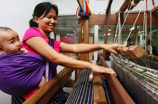  ??  ?? Lighter and happier: apar working the weaving loom with her six-month-old daughter.