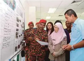  ?? PIC BY ADI SAFRI ?? Deputy Prime Minister Datuk Seri Dr Wan Azizah Wan Ismail and Johor Health, Environmen­t and Agricultur­e Committee chairman Dr Sahruddin Jamal (right) getting a briefing from Johor Fire and Rescue Department director Datuk Yahaya Madis at the district Disaster Management Committee operation room at the Pasir Gudang Municipal Council headquarte­rs in Johor Baru yesterday.