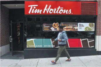  ?? CP FILE PHOTO ?? A pedestrian walks past a Tim Hortons coffee shop in downtown Toronto.