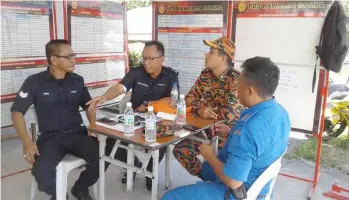  ??  ?? Personnel from Bomba, police and Civil Defence Force man the control post at the village.