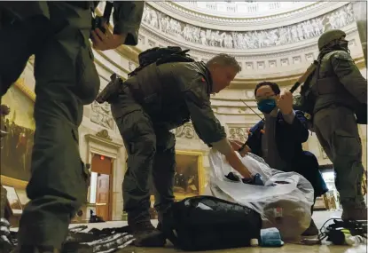  ?? ANDREW HARNIK — THE ASSOCIATED PRESS ?? Rep. Andy Kim, D-N.J., helps ATF police officers clean up debris and personal belongings strewn across the floor of the Rotunda in the early morning hours Thursday after protesters stormed the Capitol in Washington on Wednesday.