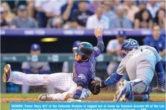  ??  ?? DENVER: Trevor Story #27 of the Colorado Rockies is tagged out at home by Yasmani Grandal #9 of the Los Angeles Dodgers in the third inning of a game at Coors Field on Saturday in Denver, Colorado. — AFP