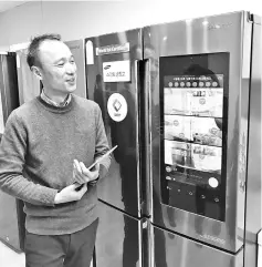  ??  ?? Korea Associatio­n of Smart Home convergenc­e standard division manager Lee Kwang-Jo shows the smart fridge at the lab.